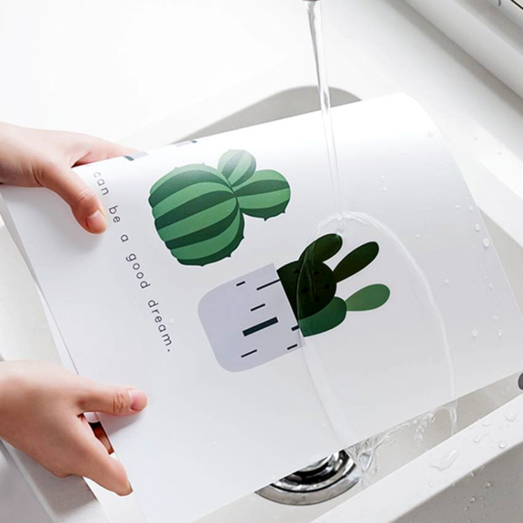 Hands rinsing the cactus placemat under a kitchen tap with water beading on it