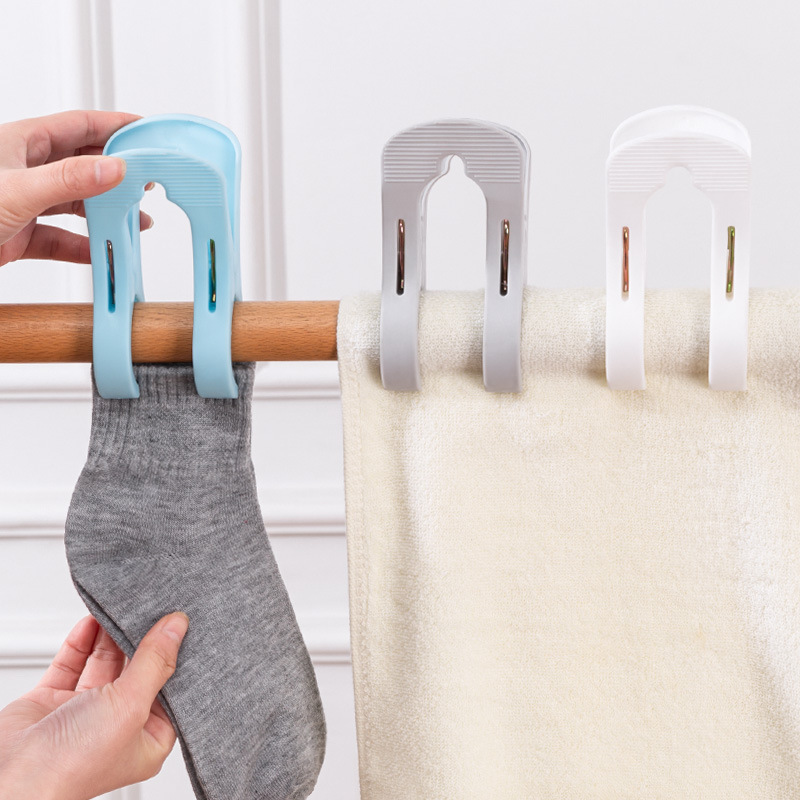 Hand hanging a grey sock from a blue clip on a wooden rod