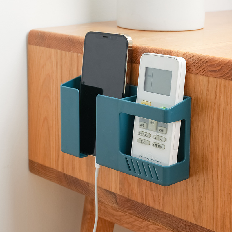 Teal wall caddy on a shelf edge with phone and remote in place