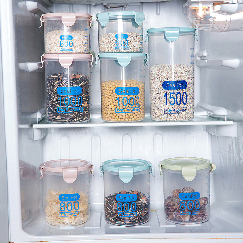Clear storage jars with coloured lids arranged on refrigerator shelves holding seeds and grains
