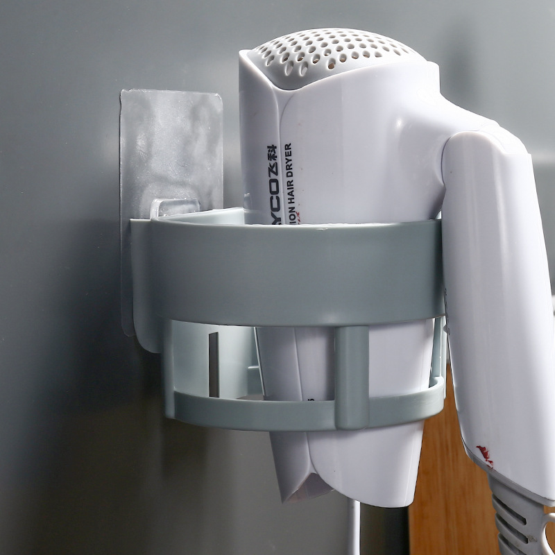 Grey holder gripping a white hair dryer barrel against a wall
