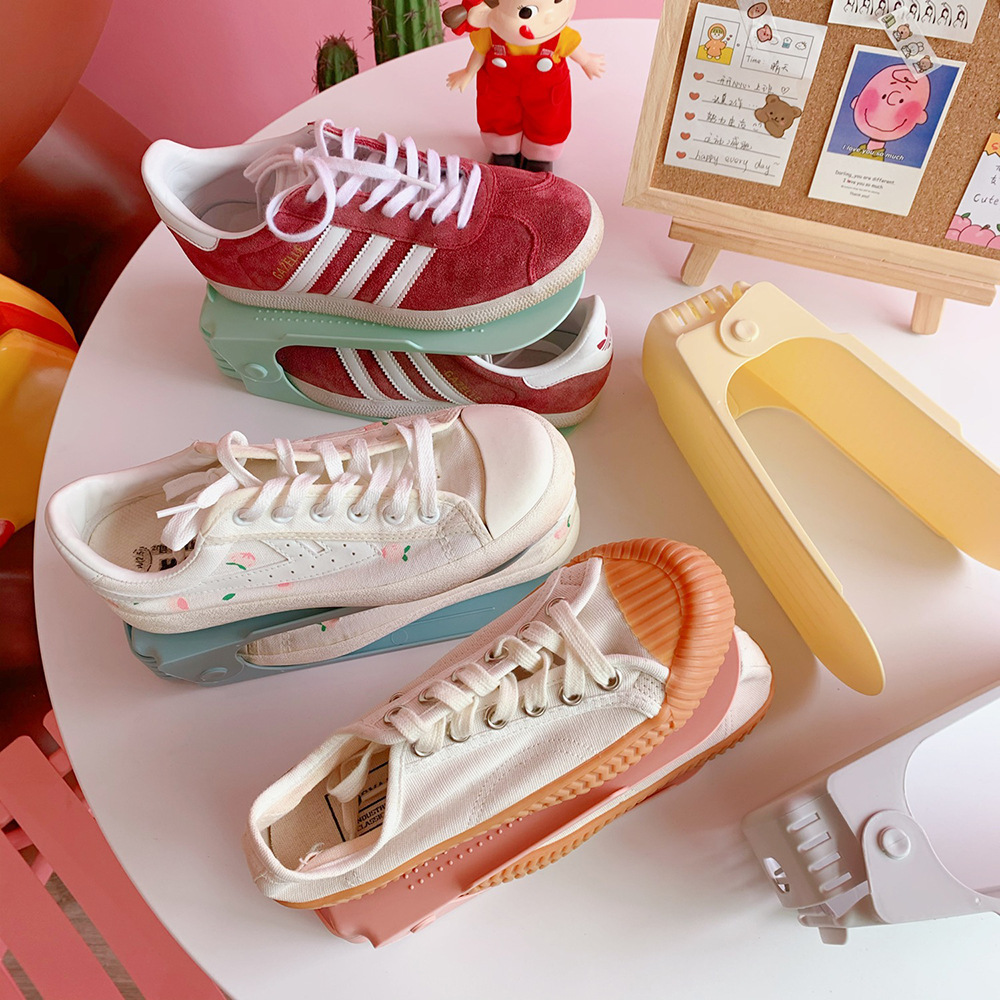 Sneakers arranged on mint and pink shoe racks on a round white table