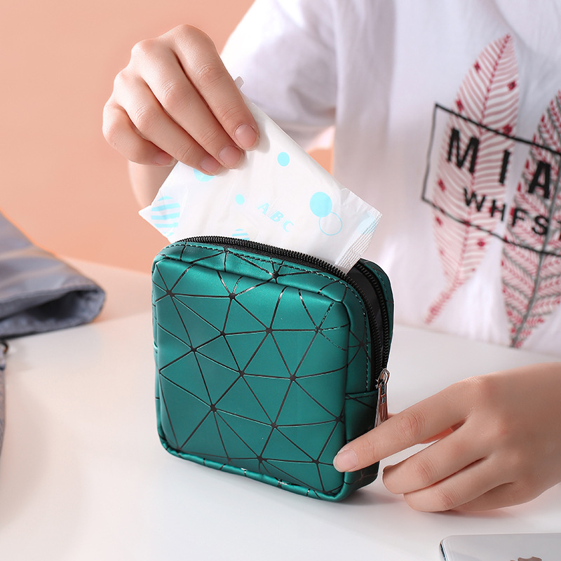 Hand pulling a pad from a teal pouch on a white desk