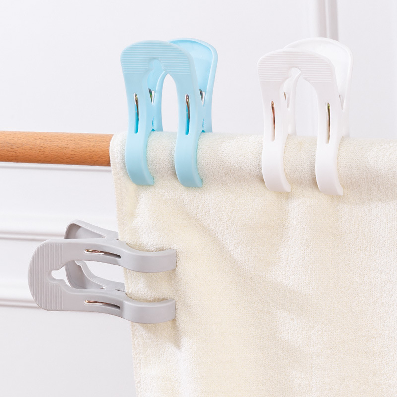 Blue, white and grey clips gripping a cream towel over a rail