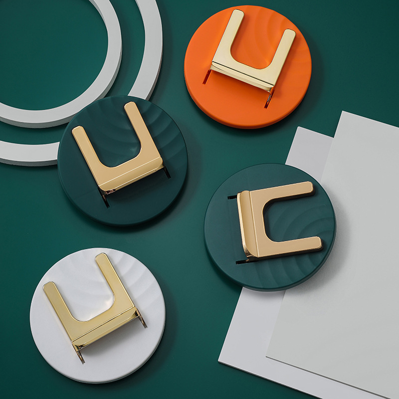Four colorway holders with gold cradles on a green backdrop