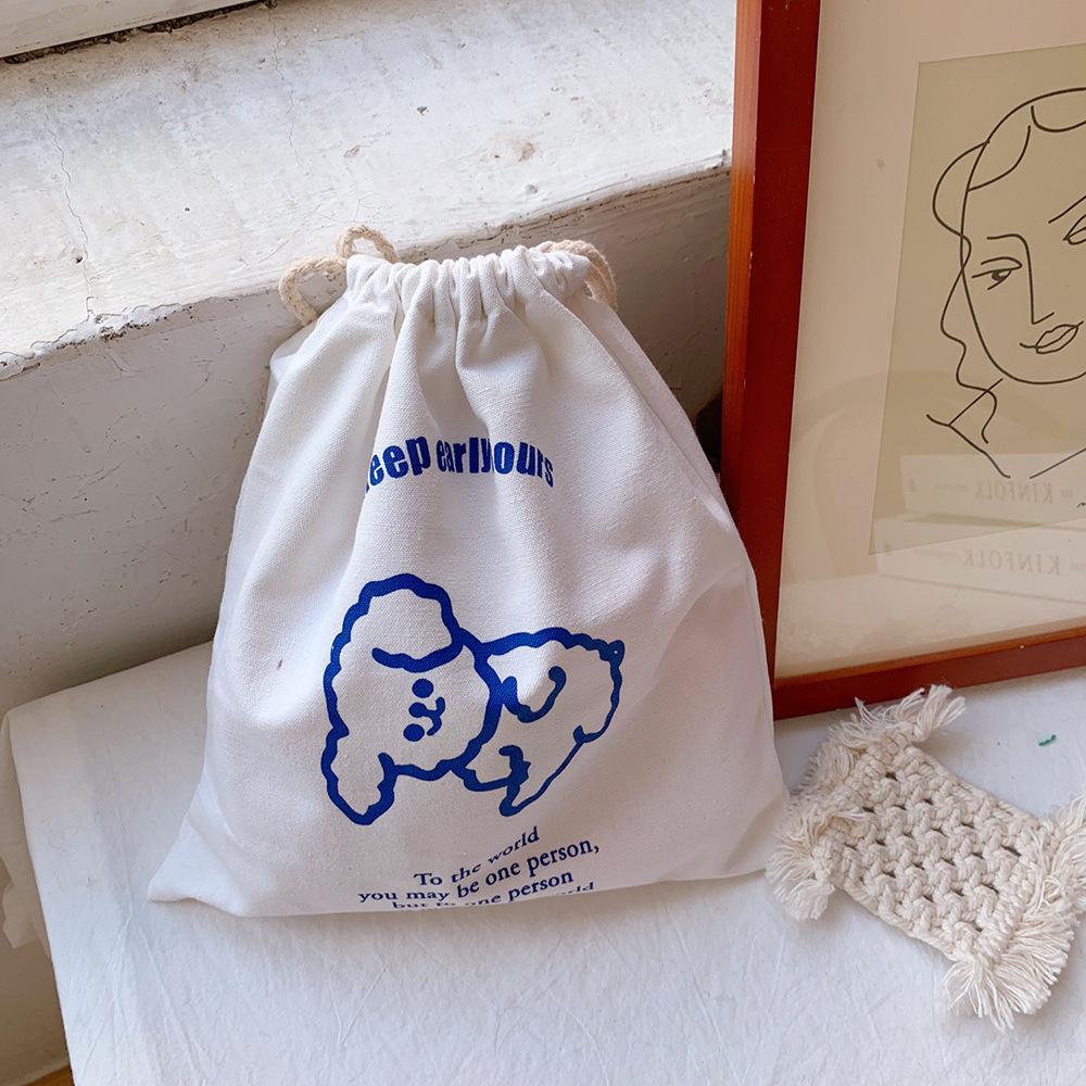 Close-up of cream canvas pouch with blue poodle print and drawstring top