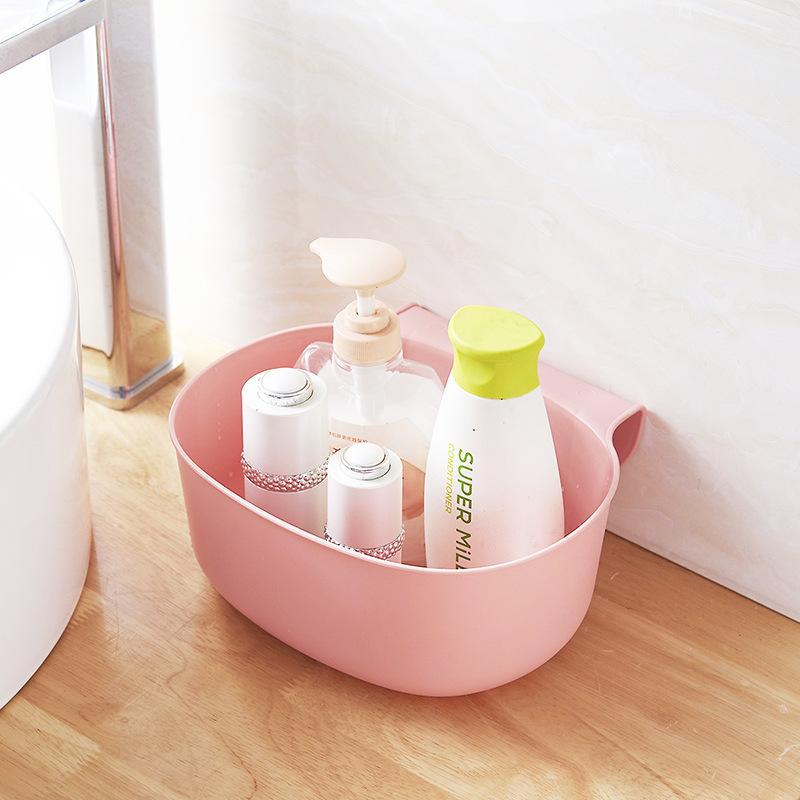 Pink bin on a cabinet door holding standard size shampoo and lotion bottles
