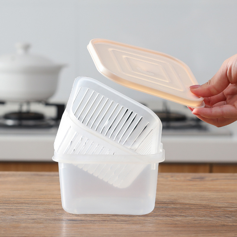 Hand lifting the peach lid off a stacked clear container with drain basket