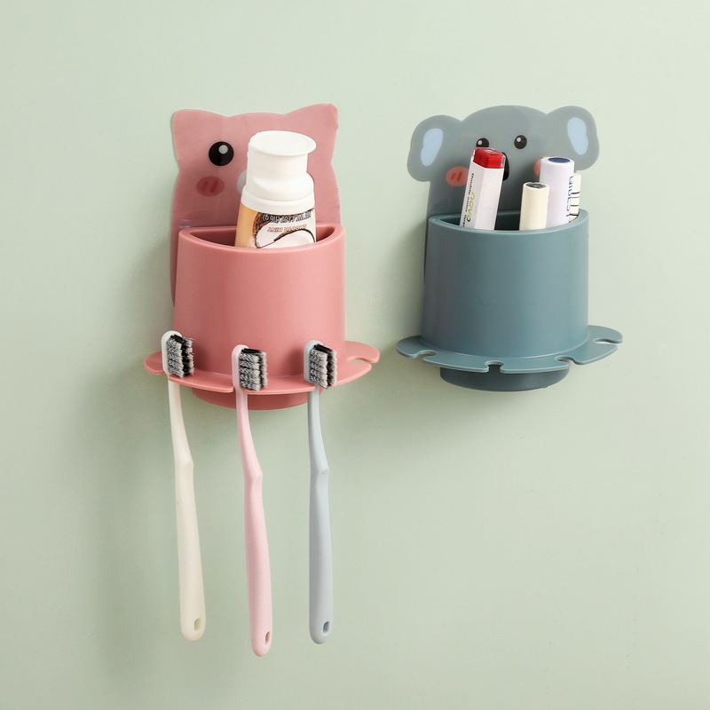 Pink pig and grey koala wall cups holding toothpaste and three toothbrushes