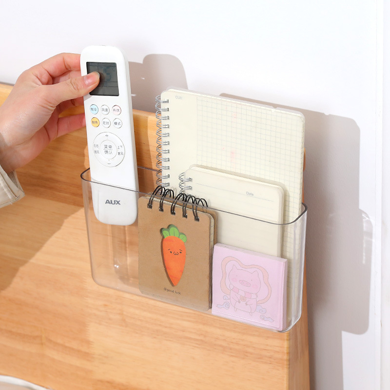 Clear wall pocket mounted on the edge of a wooden bedside board