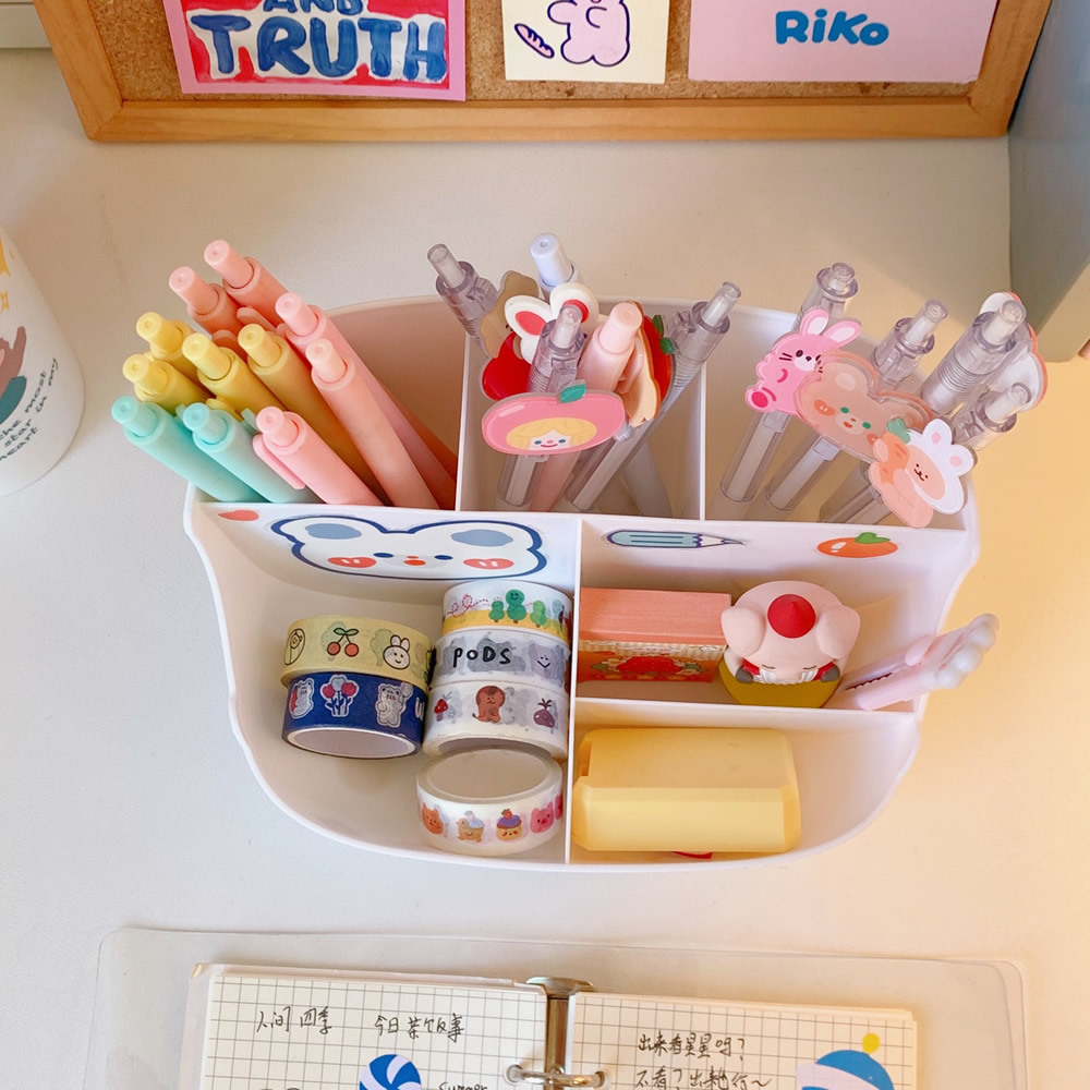 Top-down view of desk organizer with pens in compartments and washi tape rolls