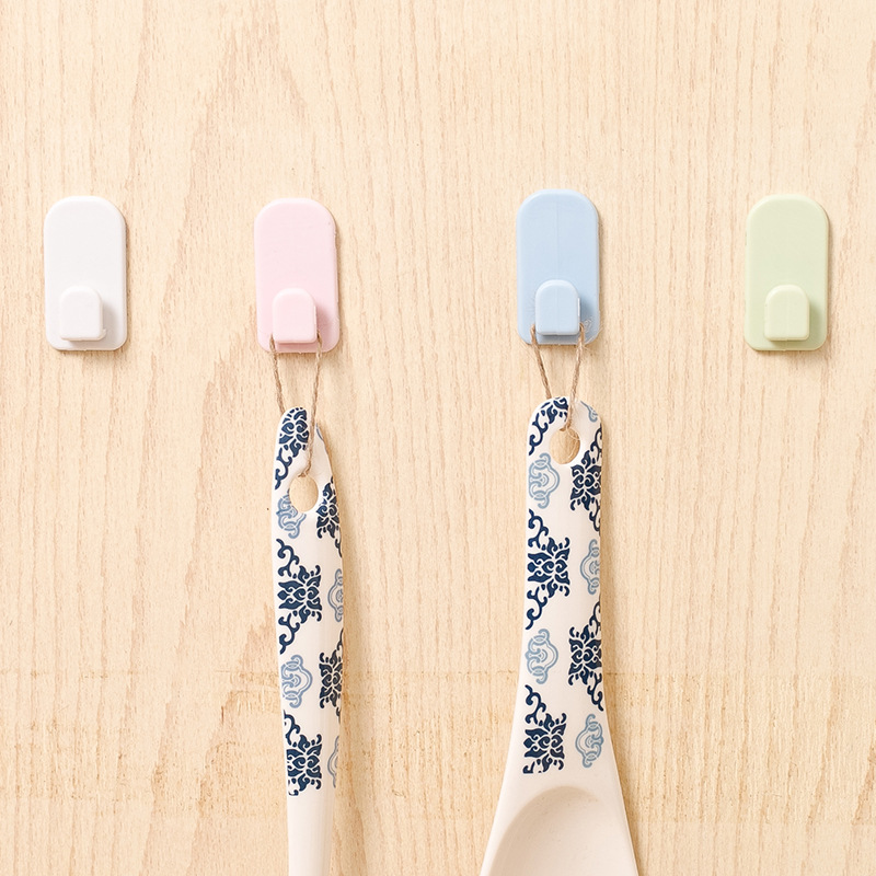 Four pastel hooks on a wall with patterned spoons hanging from them