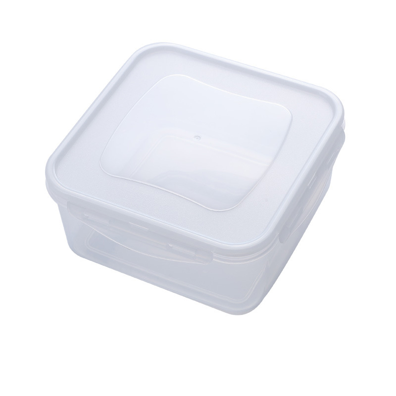Clear food container set against a kitchen counter with loose items nearby