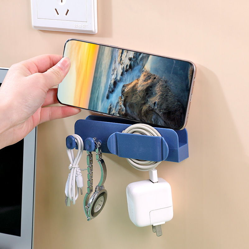 Hand placing a phone into the navy wall holder slot above a charger