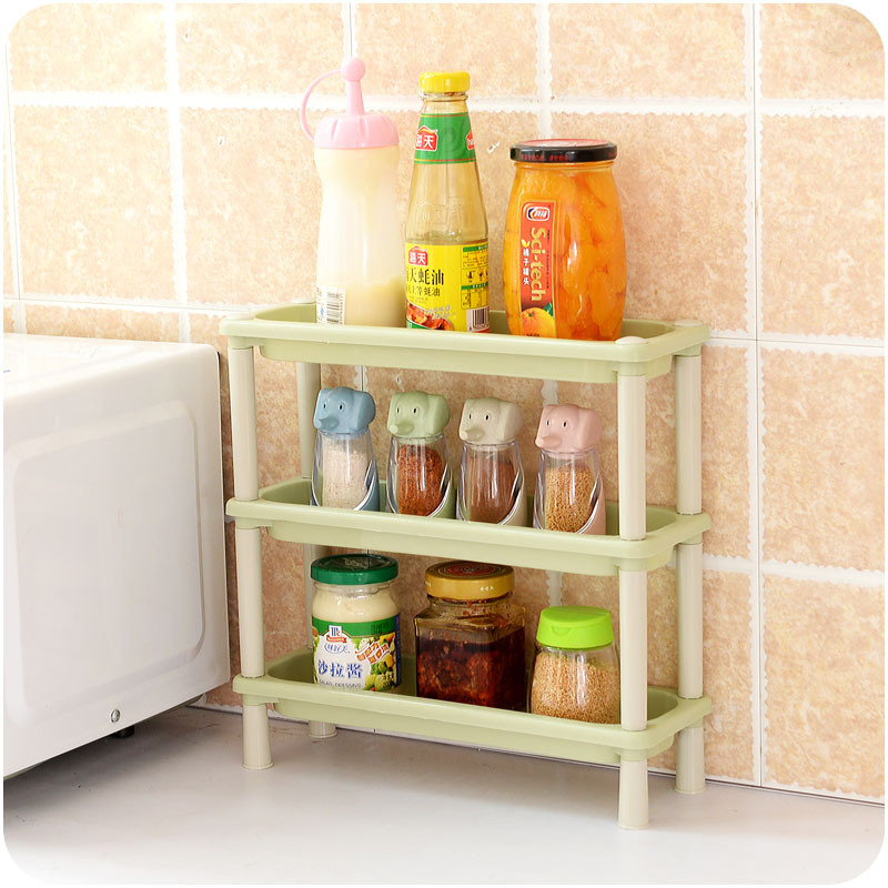 Green three-tier rack beside a microwave holding sauces, jars, and spice bottles