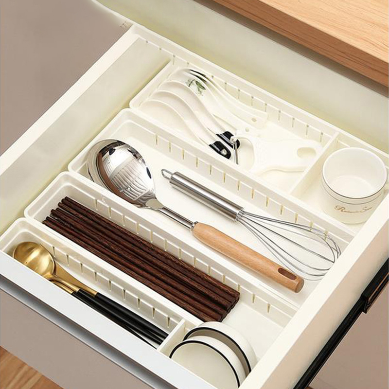 Adjustable white dividers sorting utensils into clean compartments in a drawer
