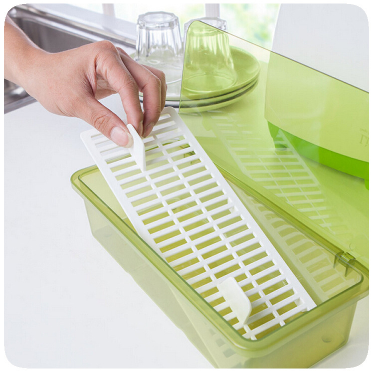 Hand lifting white slotted drain tray out of green storage box beside dish rack