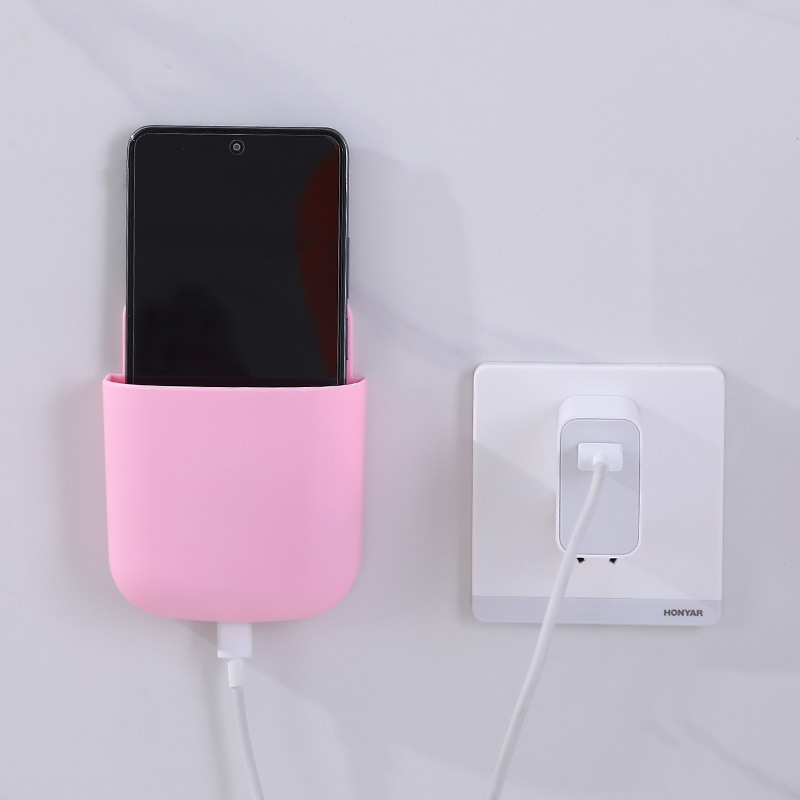 Pink wall pocket holding a smartphone beside a wall power outlet