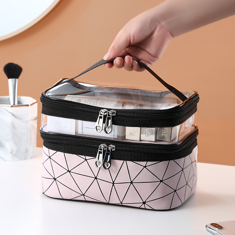 Hand lifting pink double-layer cosmetic bag by its black handle with products visible in the window