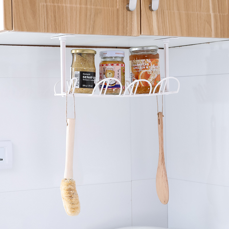White wire rack holding jars and wooden utensils under a kitchen cabinet