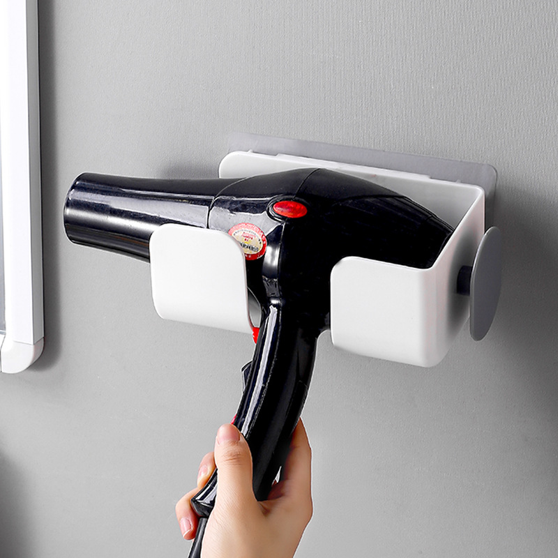 Black hair dryer lifted out of white wall bracket with one hand