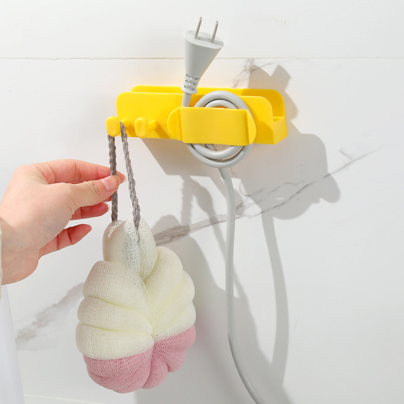 Yellow holder on a white tiled wall with a cord and a bath sponge on hooks