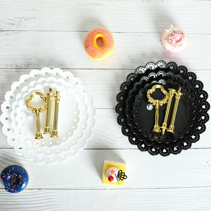Flat lay of nested black and white lace-edge plates with gold rods