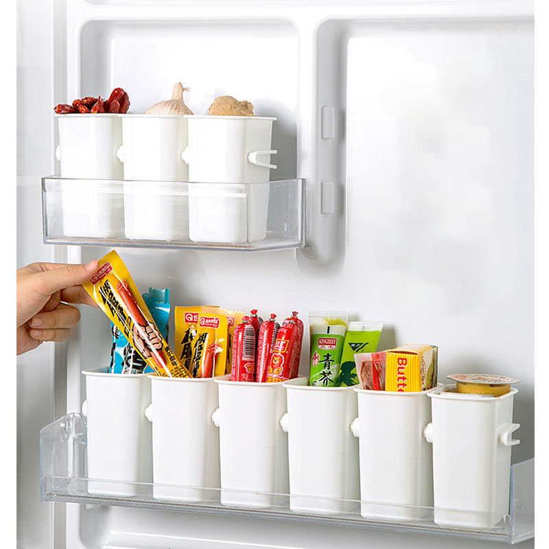 Fridge door with cups on two shelves and a hand taking a snack pack