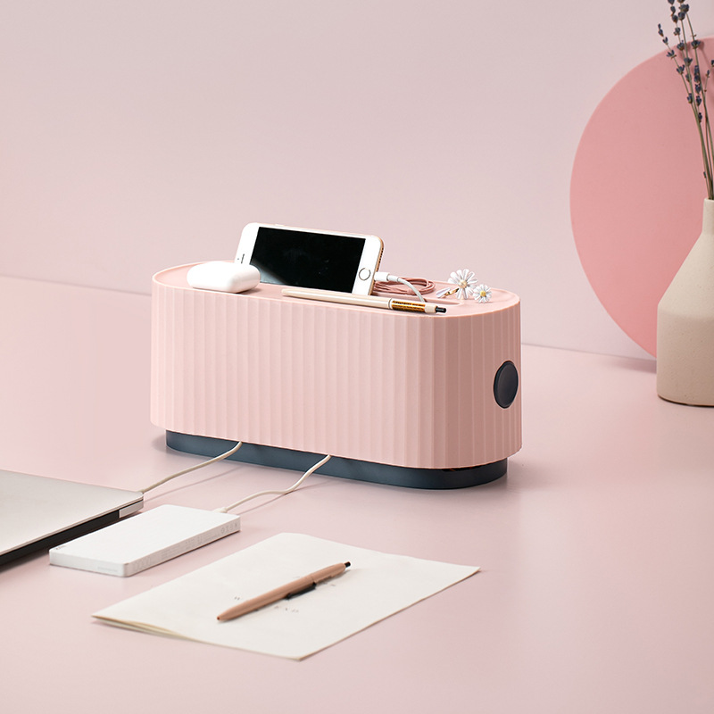 Pink cable box on a pastel desk beside a phone, pen and power bank