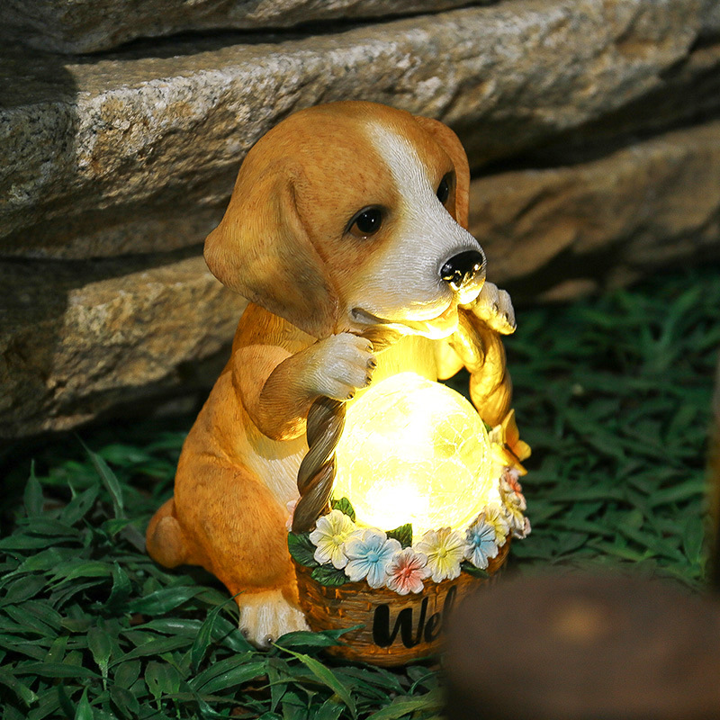Puppy ornament glowing warm among garden grass and stones at night