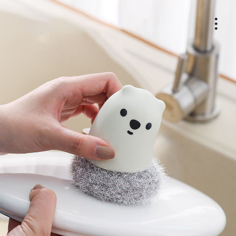 Hand gripping the cream bear pot brush over a kitchen sink