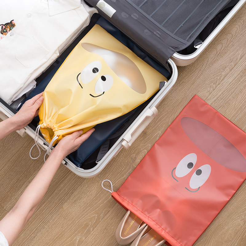 Yellow shoe bag set into an open suitcase beside a packed coral bag