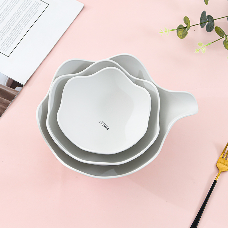 Top-down view of three nested white bowls with wavy rims and a brand mark