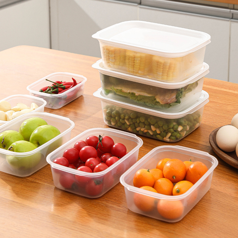 Stacked clear food boxes with white lids holding corn, greens and peas
