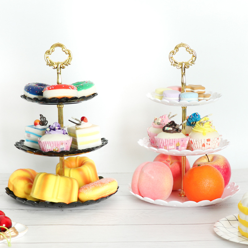 Black and white tiered stands holding donuts, bundt cakes, peaches and oranges