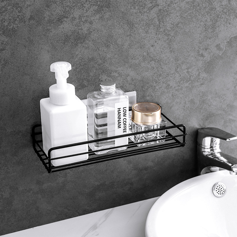 Black wire wall rack mounted beside a sink holding soap and bottles
