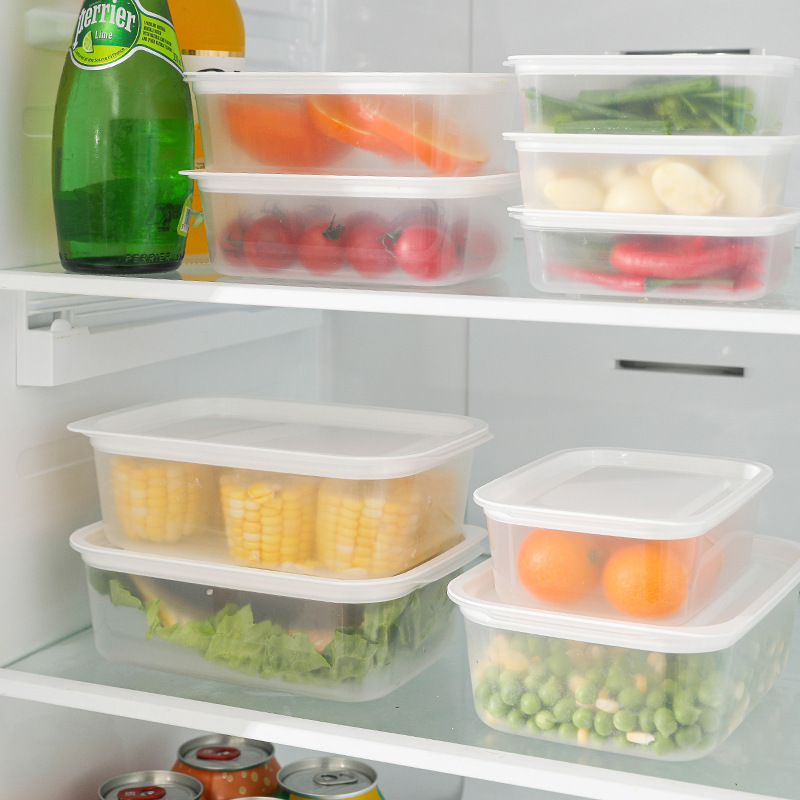 Multiple clear storage boxes with white lids filled with produce on fridge shelves