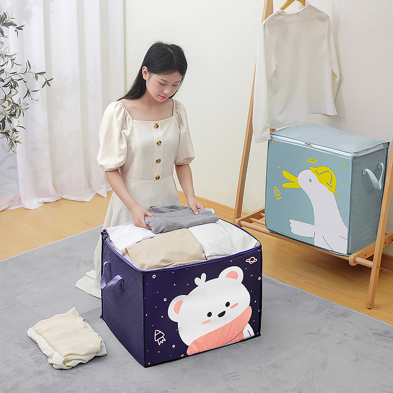 Woman packing clothes into a large navy cartoon storage bag on a grey rug