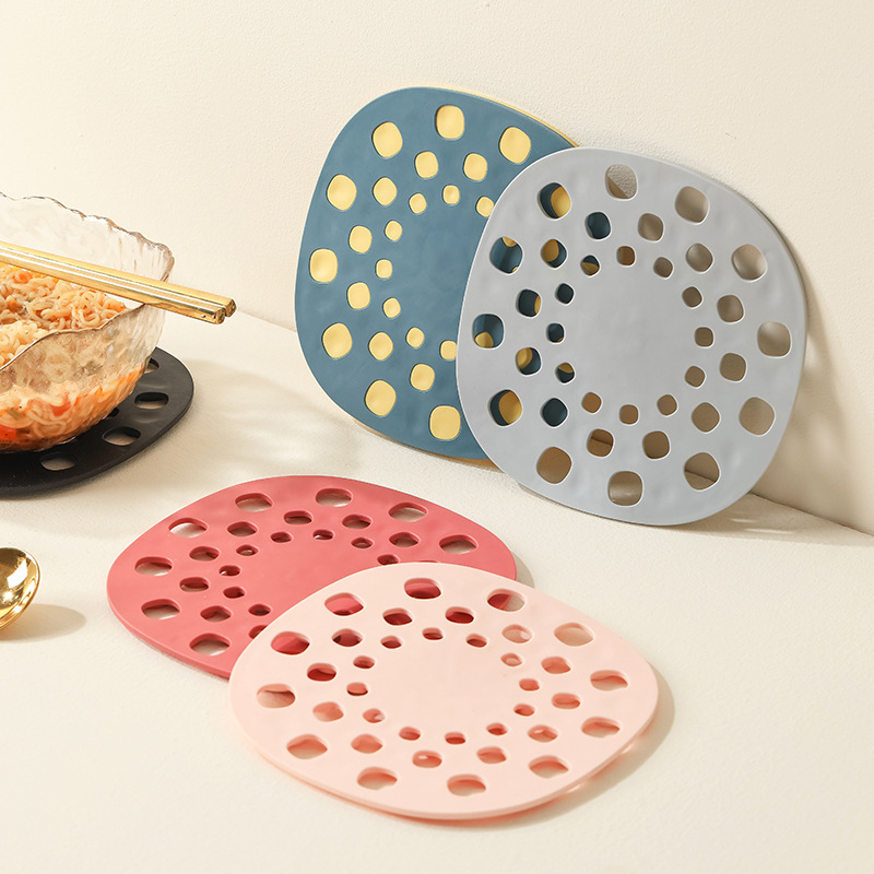 Four perforated silicone table mats in teal, grey, coral and blush pink