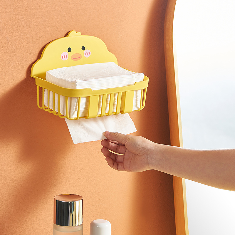 Hand pulling a tissue from a yellow chick holder mounted beside a mirror