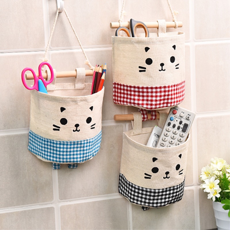 Three hanging pockets holding scissors, pencils and a remote on a tiled wall