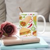 White ceramic mug with colorful food pattern, perfect for coffee or tea.