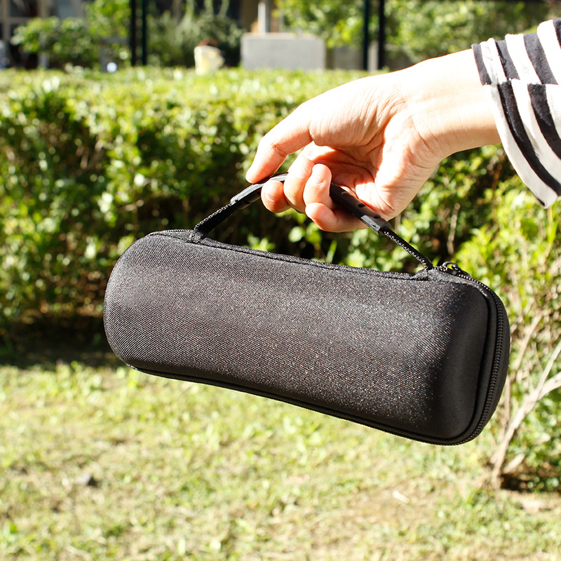 Hand holding black zippered grinder case outdoors by its handle