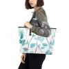 Teal leaf print PU leather tote bag carried by a woman, perfect for school or travel.