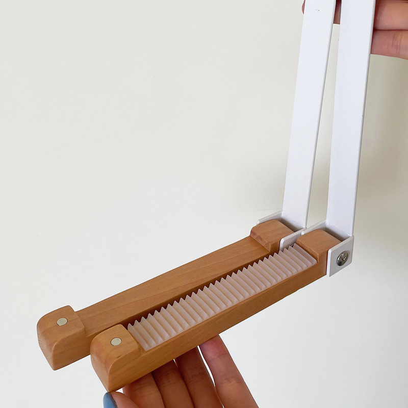 Hand holding the hook showing the ribbed rubber grip pad under the wood bar