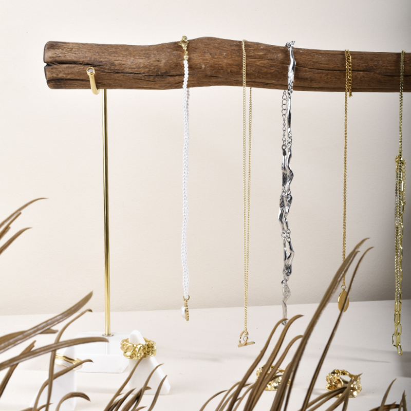 Close-up of brushed brass hook and natural wood grain on marble base