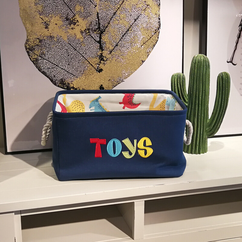Navy canvas basket with multicolor embroidered TOYS lettering and dinosaur-print lining