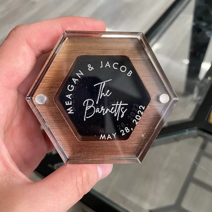 Hand holding hexagon ring box with engraved names on clear acrylic lid