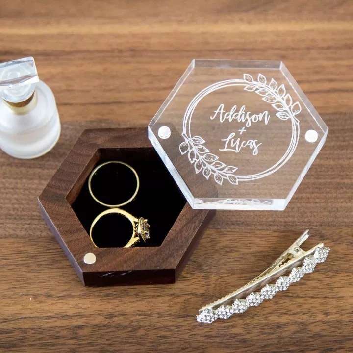 Open walnut ring box with black velvet interior and gold rings seated