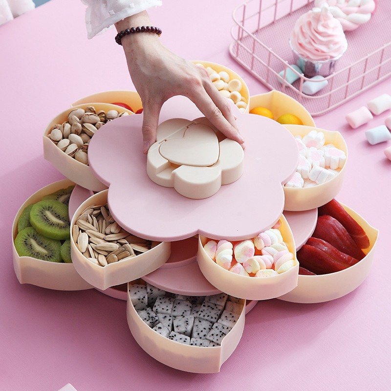 Hand turning the cream heart-shaped knob on a lotus snack tray filled with mixed nuts